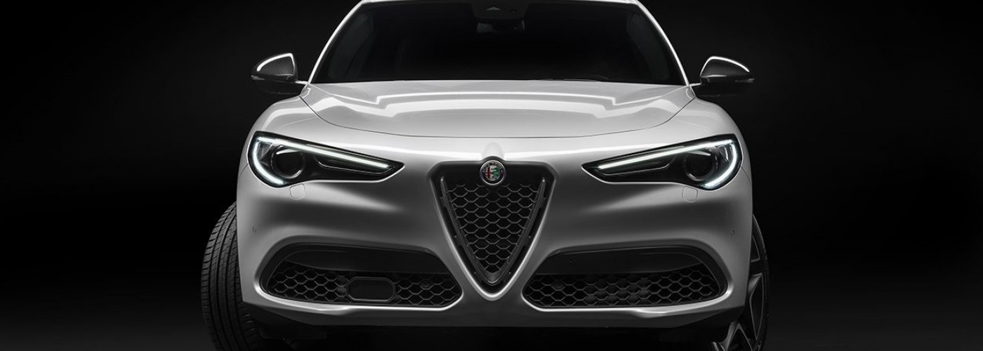 Silber grauer Alfa Romeo Stelvio TI parkiert vor schwarzem Hintergrund