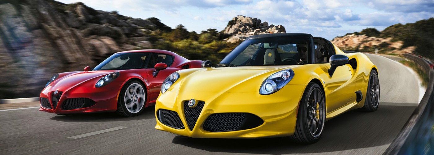 Ein roter Alfa Romeo 4C und ein gelber Alfa Romeo 4C Spider von vorne auf der Strasse bei Tageslicht.