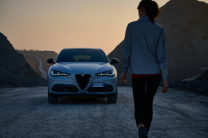 Neuer nach Facelift Alfa Romeo Stelvio in der Natur parkiert mit einer Frau rechts im Bild
